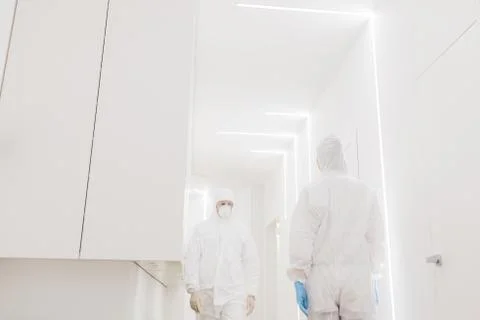 Two doctors in protective suits walk past each other during an epidemic covid in Stock Photos