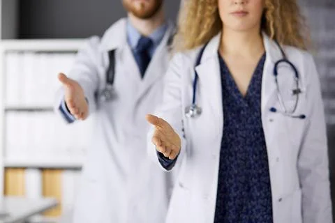 Two doctors standing and offering helping hand for shaking hand or saving life Stockfoto's