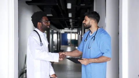 Two doctors standing in hospital corridor talking and shaking hands  Stock Footage 329052509