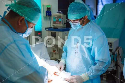 Two doctors in sterile medical clothes perform an operation in a hospital Stock Photos