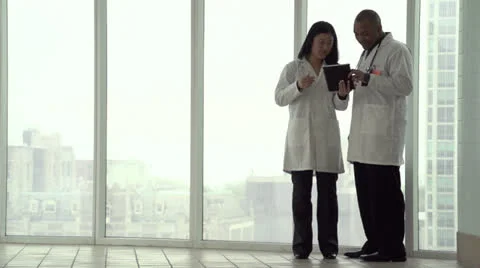 Two doctors on tablet by the window Stock Footage 24631624