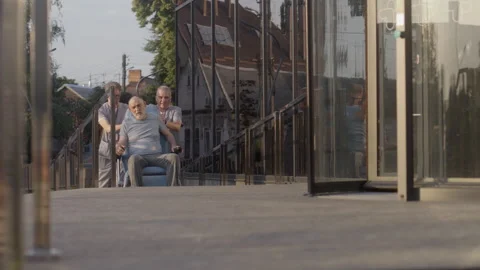 Two doctors take elderly patient with disability to the hospital Stock Footage 249863881