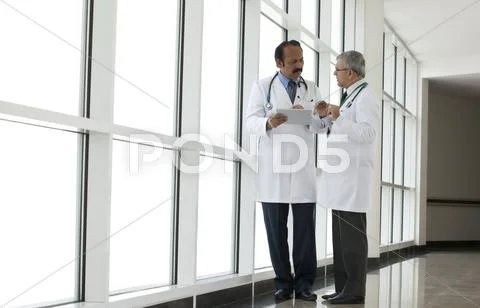 Two Doctors Talking In Corridor Of Hospital