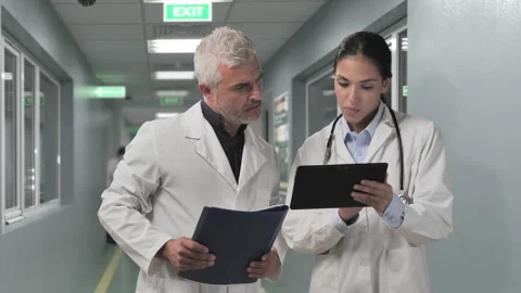Two doctors talking discussing in the hospital ward sharing patient data Stock Footage 198988489