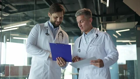 Two Doctors Talking While Reviewing Patient Notes Stock Footage 281917549