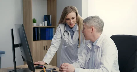 Two doctors talking at workplace looking at computer screen, analyzing results Video stock 155635450