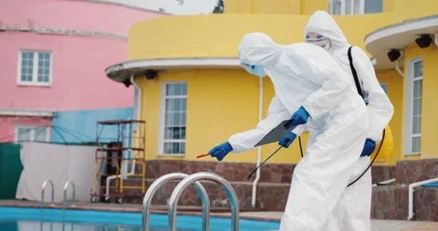 Two doctors team in protective suits disinfect swimming pool, control sanitation Stock Footage 131133476