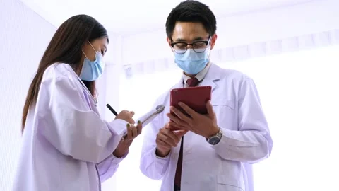 Two doctors wearing face mask talking at hospital. Video stock 133355747