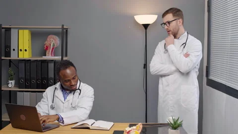 Two doctors in white lab coats analyzing test results on laptop Stock-Footage 276224030