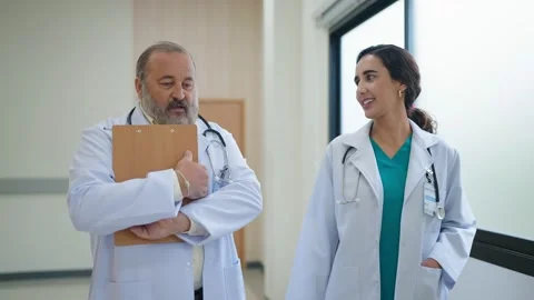 Two doctors in white uniform walking and talking in the corridor at the hospital Stock-Footage 234507716
