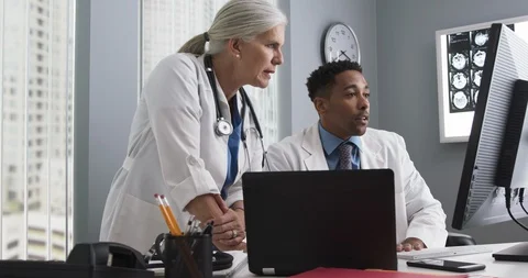 Two doctors working inside medical office looking at computer monitor and typing Video stock 98261300