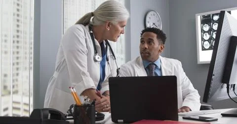 Two doctors working inside medical office looking at computer monitor and typ Stock-Fotos
