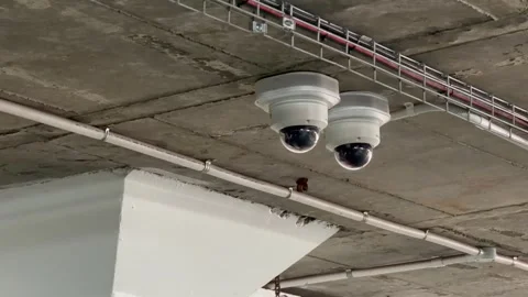 Two Dome CCTV Security Cameras Mounted on Concrete Ceiling in Parking Garage Stock Footage 345518967