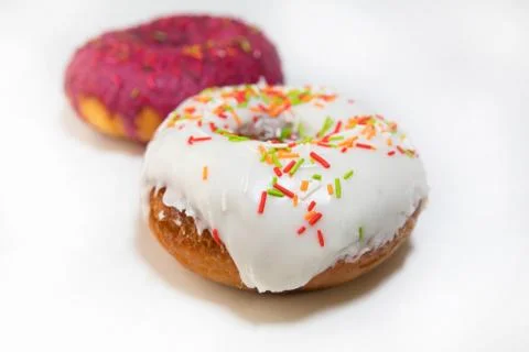Two donuts covered with red glaze side view on white background Stock Photos