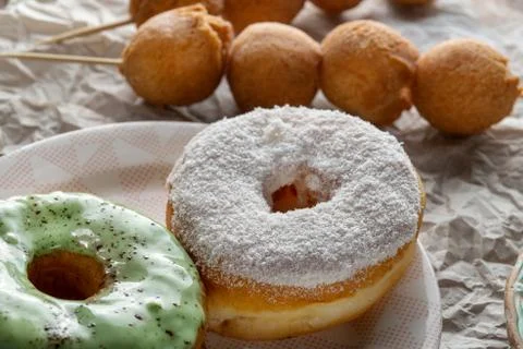 Two donuts, one with icing, the second is sprinkled with coconut chips. Stock Photos