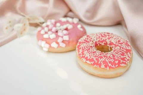 Two donuts with sprinkles and marshmallows, on a white background Foto stock