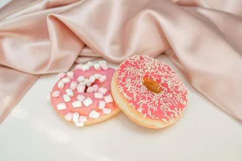 Two donuts with sprinkles and marshmallows, on a white background Stock Photos