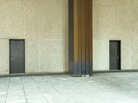 Two doors stand beside a column in a concrete space during daytime under na.. Stockfoto's
