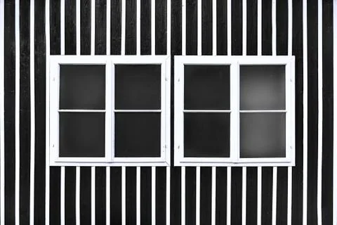 Two double white windows on a black wall with white slats. Stock Photos
