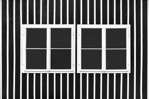 Two double white windows on a black wall with white slats. Stock Photos