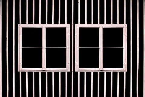 Two double white windows on a black wall with white slats. Stock Photos