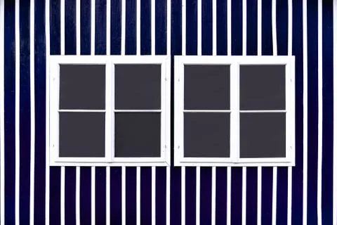 Two double white windows on a blue wall with white slats. Stock Photos