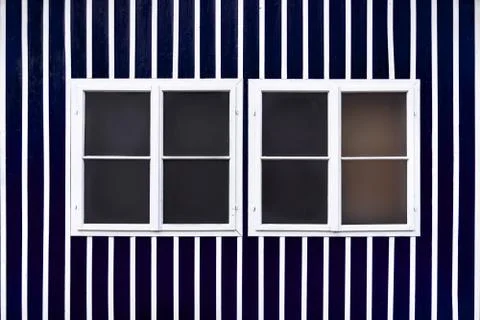 Two double white windows on a blue wall with white slats. Stock Photos