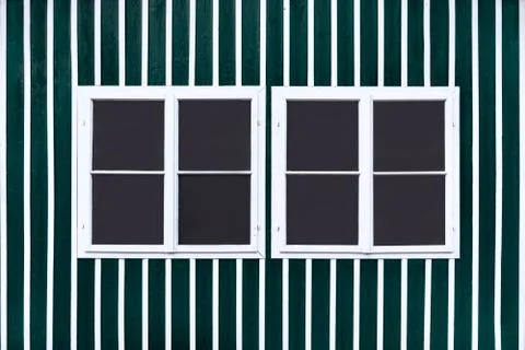 Two double white windows on a green wall with white slats. Stock Photos