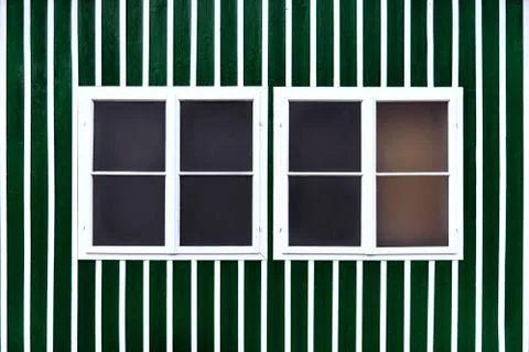 Two double white windows on a green wall with white slats. Stock Photos