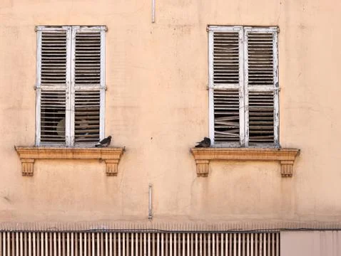 Two doves sitting at the closed windows of the old house Stock Photos