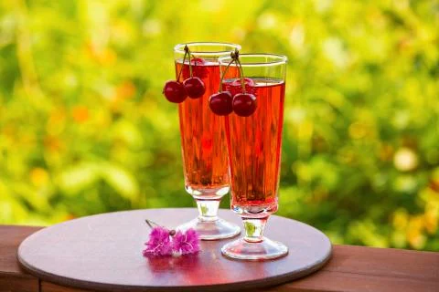 Two drinks, red drink, cherries and flowers Stock Photos