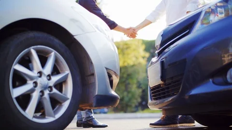 Two drivers shake hands after a small road accident. In the foreground there are Stock Footage 94966343