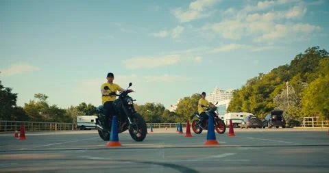 Two driving instructors in yellow t-shirts hone their skills in motorcycle Stock Footage 249435428