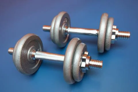 Two dumbbells on a blue background Stock Photos