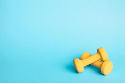Two dumbbells on blue background. Stock Photos