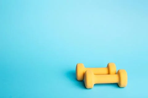 Two dumbbells on blue background. Stock Photos