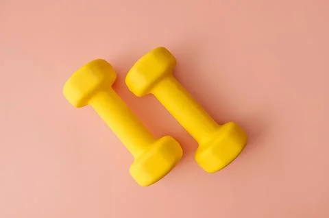 Two dumbbells on pink background, flat lay. Space for text Stock Photos