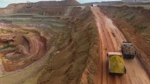 Two dump trucks carry ore from the quarry. Panorama of the mine. Barkhan sands Stock Footage 75041429