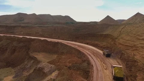 Two dump trucks carry ore from the quarry. Panorama of the mine. Barkhan sands Stockbeeldmateriaal 75288651