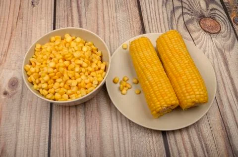 Two ears of boiled corn in a plate and a grain of corn on the table. Healthy  Stock Photos