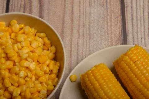 Two ears of boiled corn in a plate and a grain of corn on the table. Healthy  Stock Photos