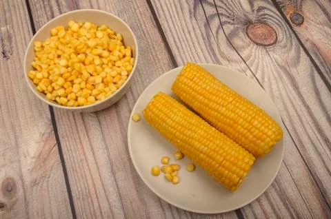 Two ears of boiled corn in a plate and a grain of corn on the table. Healthy  Stock Photos