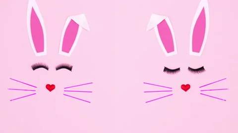 Two Easter bunnies blinking with eye lashes on pink background. Stop motion Stock Footage 150260349