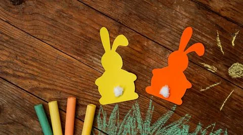 Two Easter bunnies made of paper. Drawn with colored chalk grass and sun Stock Photos
