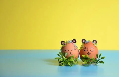 Two Easter eggs with cute faces on a yellow-blue background. Easter. Stock Photos