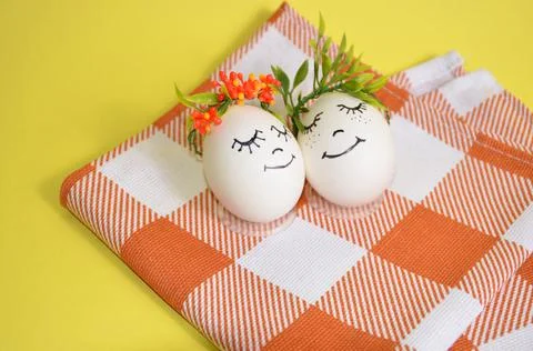 Two Easter eggs with cute little faces on a yellow background. Spring. Easter. Stock Photos
