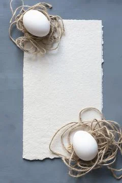 Two Easter eggs decorated with twine in the shape of a nest on a gray texture Foto stock