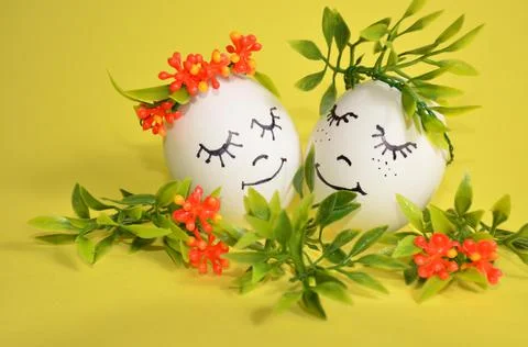 Two Easter eggs in flowers on a yellow background. Stock Photos
