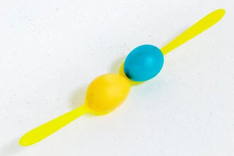 Two Easter eggs lie on yellow spoons. On white background. Stock Photos