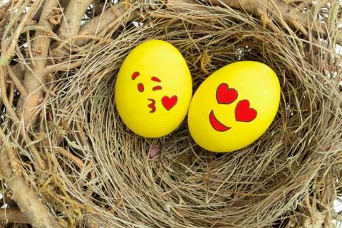 Two Easter eggs, one in love and other kissing, placed in a bird nest Stock Photos